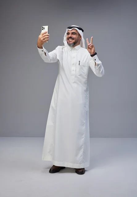 رجل سعودي بالزي التقليدي يلتقط صورة سيلفي في الاستوديو