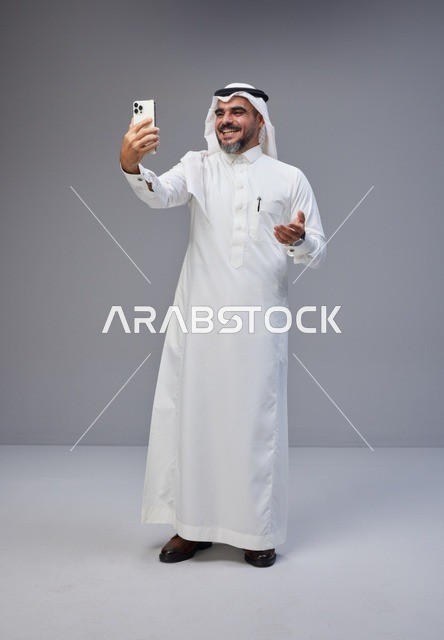 رجل سعودي بالزي التقليدي يلتقط سيلفي بالهاتف