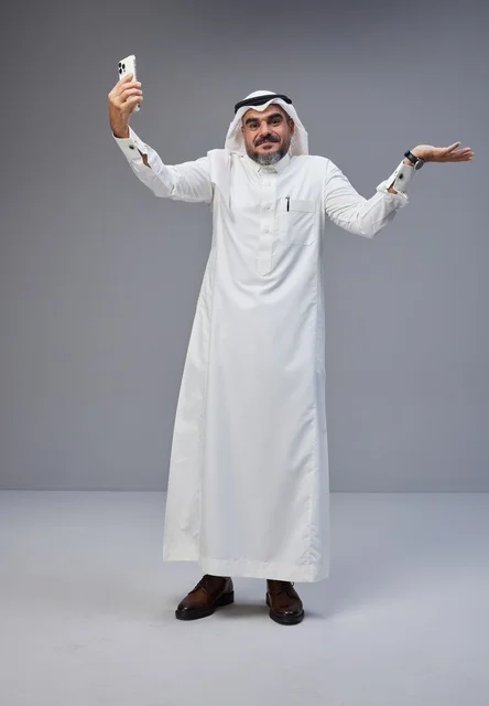 رجل سعودي بالزي التقليدي يلتقط صورة سيلفي في الاستوديو