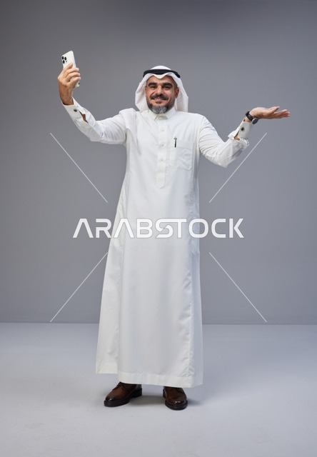 رجل سعودي بالزي التقليدي يلتقط سيلفي بالهاتف