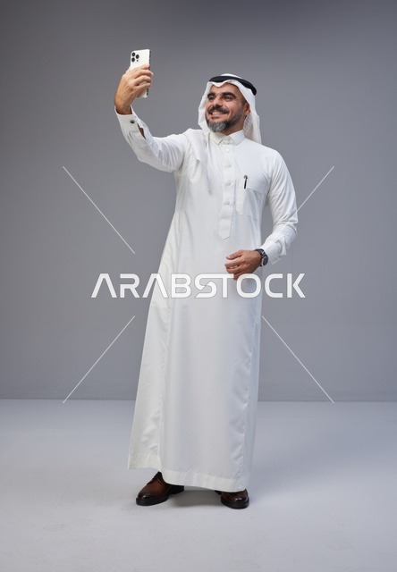 رجل سعودي يلتقط سيلفي بالهاتف في استوديو