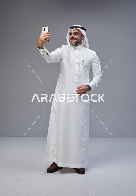 رجل سعودي بالزي التقليدي يلتقط سيلفي بالجوال
