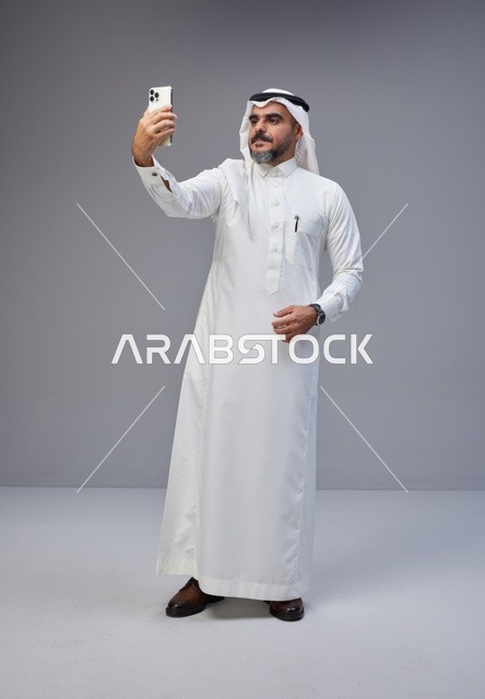 Saudi Man in Traditional Thobe Taking Studio Selfie