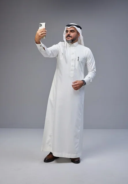 رجل سعودي بالزي التقليدي يلتقط سيلفي في الاستوديو