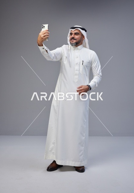 رجل سعودي بالزي التقليدي يلتقط سيلفي بالهاتف