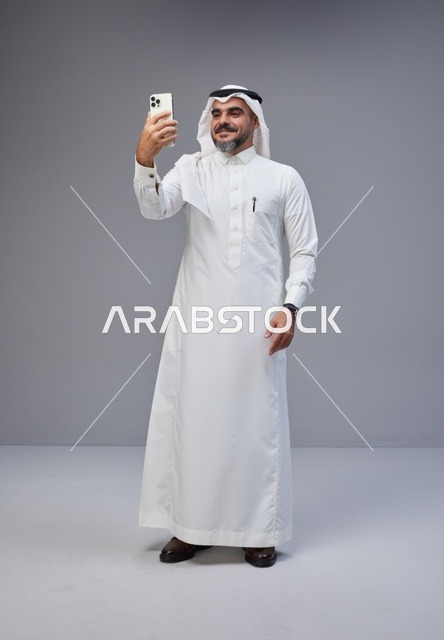 رجل سعودي بالزي التقليدي يلتقط صورة سيلفي بالجوال