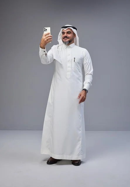 رجل سعودي بالزي التقليدي يلتقط صورة سيلفي بالجوال