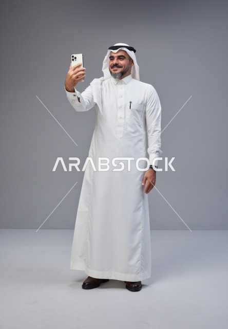 Saudi Man in Traditional Thobe Taking Smartphone Selfie
