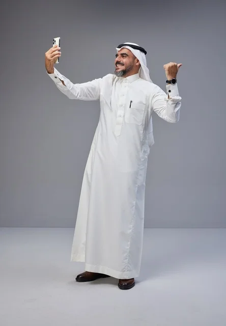 رجل سعودي بالزي التقليدي يلتقط صورة سيلفي في الاستوديو
