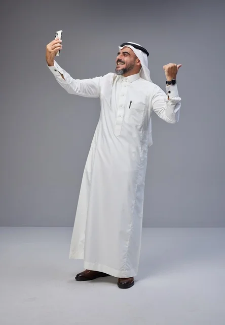 رجل سعودي بالزي التقليدي يلتقط سيلفي في الاستوديو