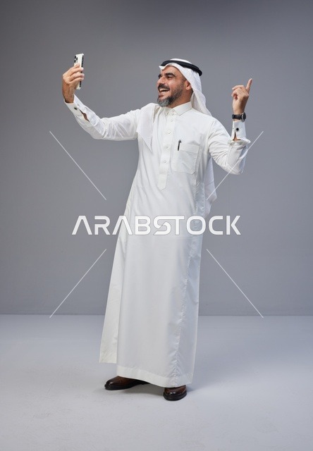 رجل سعودي بالزي التقليدي يلتقط صورة سيلفي بالهاتف