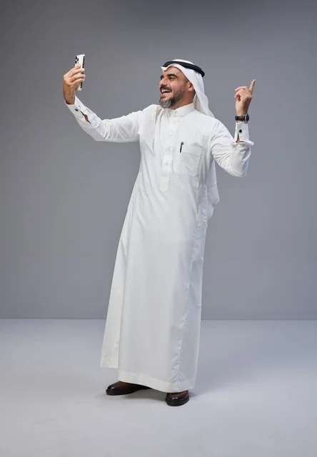 رجل سعودي بالزي التقليدي يلتقط صورة سيلفي بالهاتف