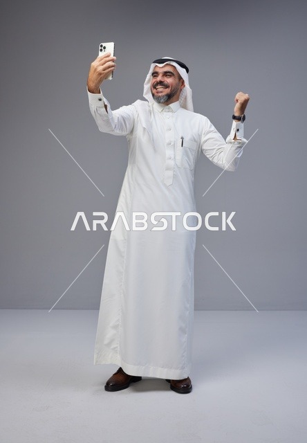 رجل سعودي بالثوب التقليدي يلتقط سيلفي في الاستوديو