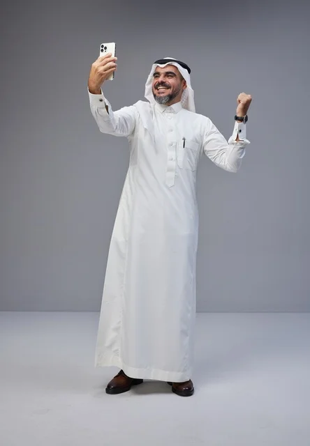 رجل سعودي بالثوب التقليدي يلتقط سيلفي في الاستوديو