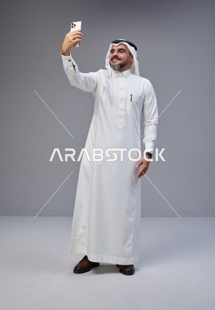 رجل سعودي بالزي التقليدي يلتقط سيلفي بالهاتف