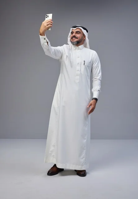 رجل سعودي بالزي التقليدي يلتقط سيلفي بالهاتف