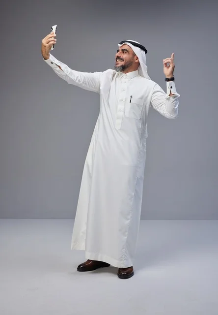 رجل سعودي بالزي التقليدي يلتقط سيلفي بالهاتف الذكي