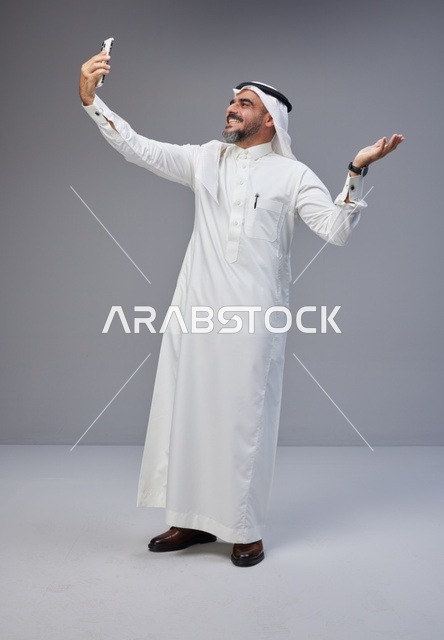 رجل سعودي بالزي التقليدي يلتقط سيلفي بالهاتف