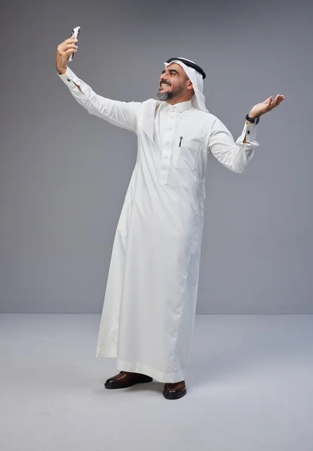 Saudi Man in Traditional Thobe Taking Smartphone Selfie
