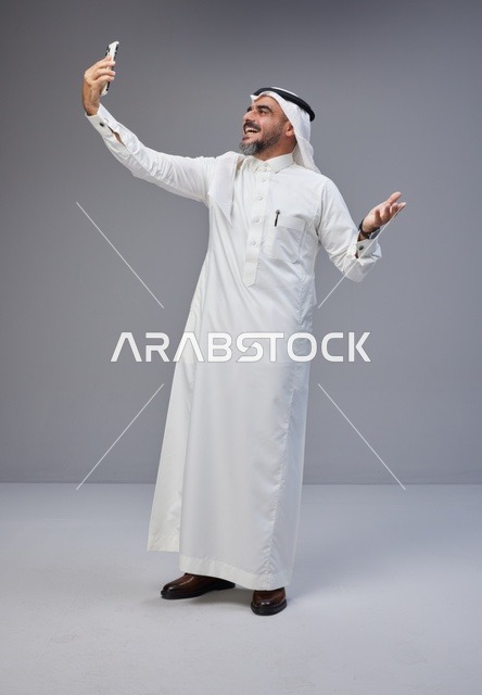 رجل سعودي بالزي التقليدي يلتقط سيلفي بالهاتف