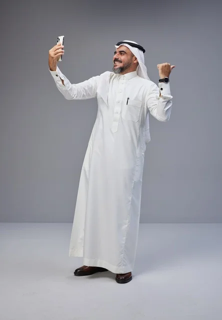 رجل سعودي بالزي التقليدي يلتقط صورة سيلفي بالجوال