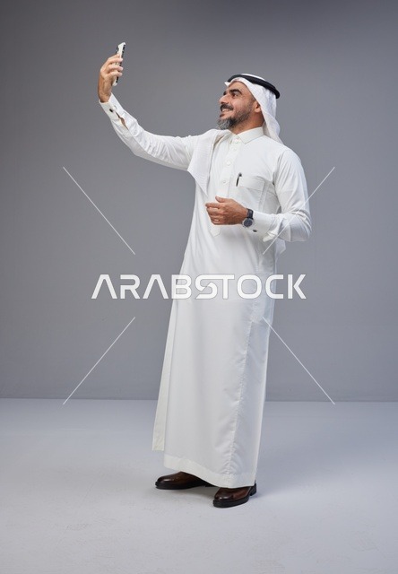 رجل سعودي بالزي التقليدي يلتقط سيلفي بالهاتف