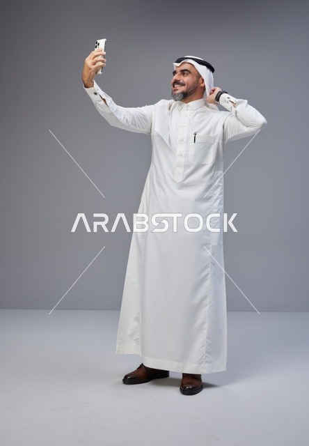 Saudi Man in Traditional Thobe Taking Smartphone Selfie