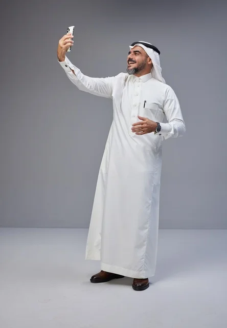 رجل سعودي بالزي التقليدي يلتقط سيلفي بالهاتف