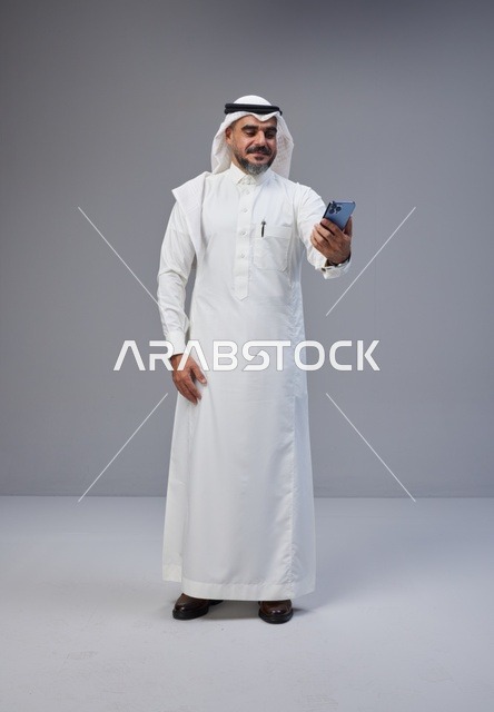 رجل سعودي بالزي التقليدي يلتقط سيلفي في الاستوديو