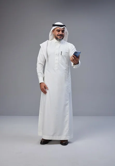 رجل سعودي بالزي التقليدي يستخدم الهاتف الذكي في الاستوديو