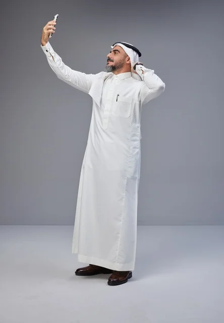 رجل سعودي بالزي التقليدي يلتقط سيلفي في الاستوديو