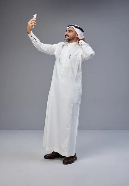 رجل سعودي بالزي التقليدي يلتقط سيلفي بالهاتف الذكي