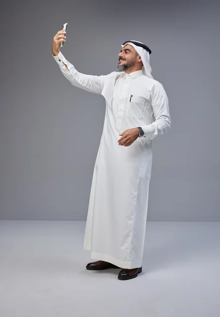 رجل سعودي بالزي التقليدي يلتقط سيلفي بالهاتف