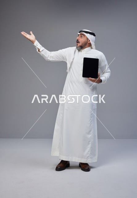 Surprised Saudi Man Holding Tablet in Studio