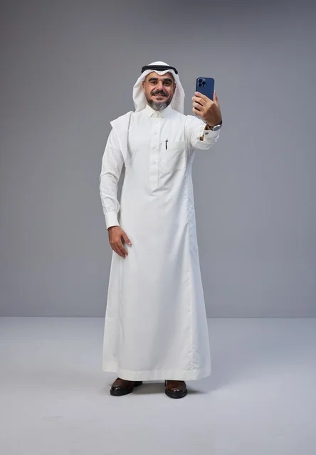 رجل سعودي بالزي التقليدي يلتقط سيلفي بالهاتف الذكي