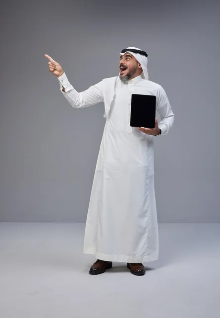 Saudi Man with Tablet Pointing Upward on Grey Background