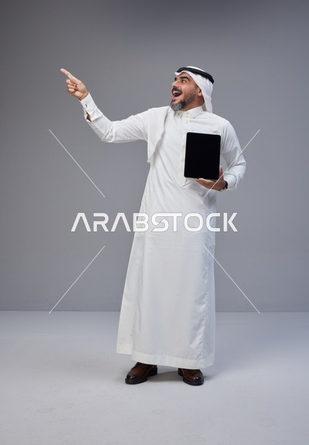 Saudi Man in Traditional Thobe Holding Tablet and Pointing