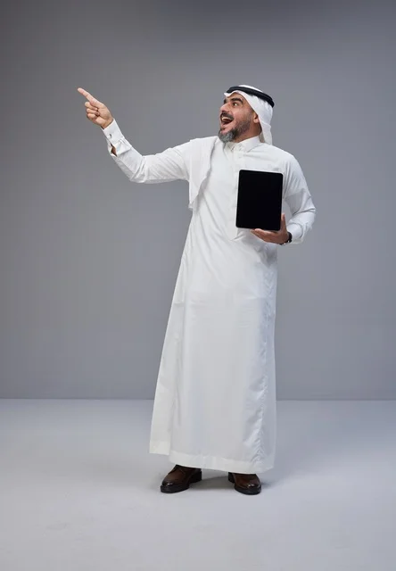 Saudi Man in Traditional Thobe Holding Tablet and Pointing