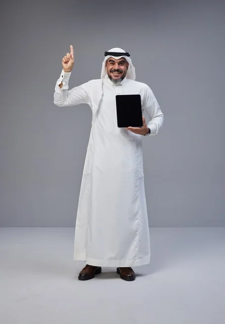 Saudi Man Holding Tablet Pointing Upward in Studio
