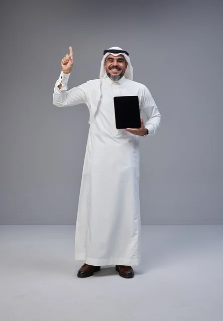 Saudi Man Holding Tablet and Pointing Up in Studio