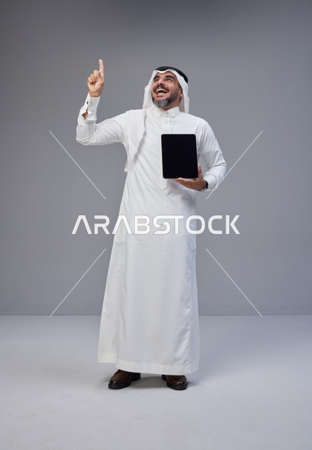 Saudi Man in Traditional Thobe Holding Tablet Pointing Up
