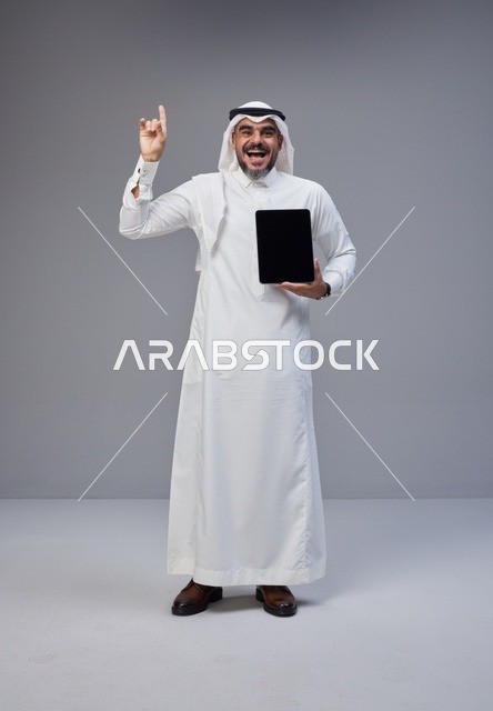 Saudi Man Holding Tablet Pointing Up in Studio
