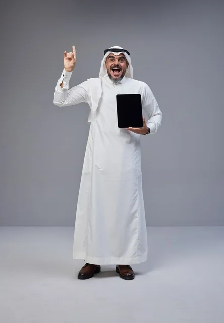 Saudi Man Holding Tablet Pointing Upward in Studio
