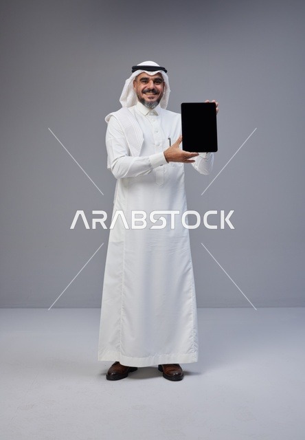 رجل سعودي يحمل جهاز لوحي بشاشة فارغة