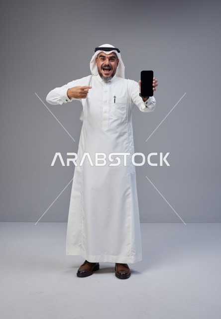 Saudi Man in Thobe Pointing at Smartphone Screen