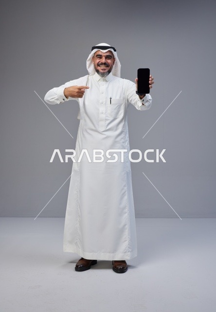 Saudi Man in Thobe Pointing to Blank Smartphone Screen