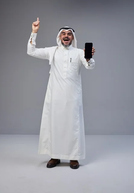 رجل سعودي يحمل هاتف بشاشة فارغة في الاستوديو