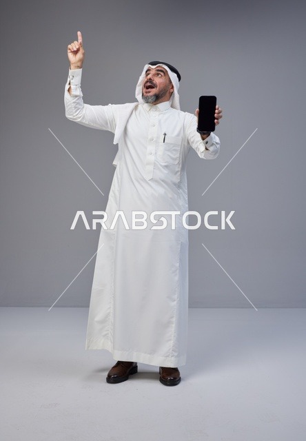 Saudi Man Holding Smartphone Pointing Up in Studio