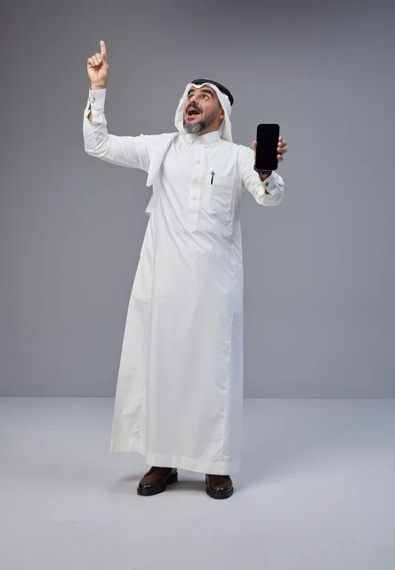 Saudi Man Holding Smartphone Pointing Up in Studio