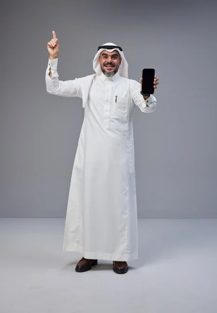 رجل سعودي يحمل هاتفاً بشاشة فارغة بوضعية الوقوف